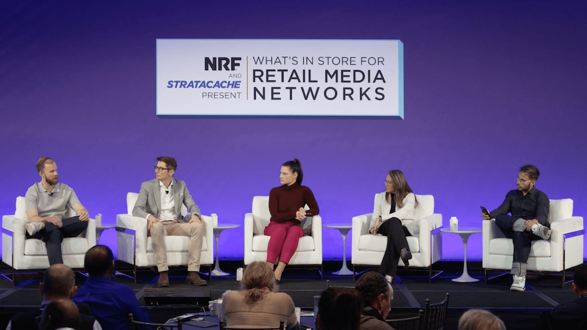 Panelists sit on stage in white chairs in front of a sign that reads "NRF and Stratacache Present What's In-Store for Retail Media Networks"